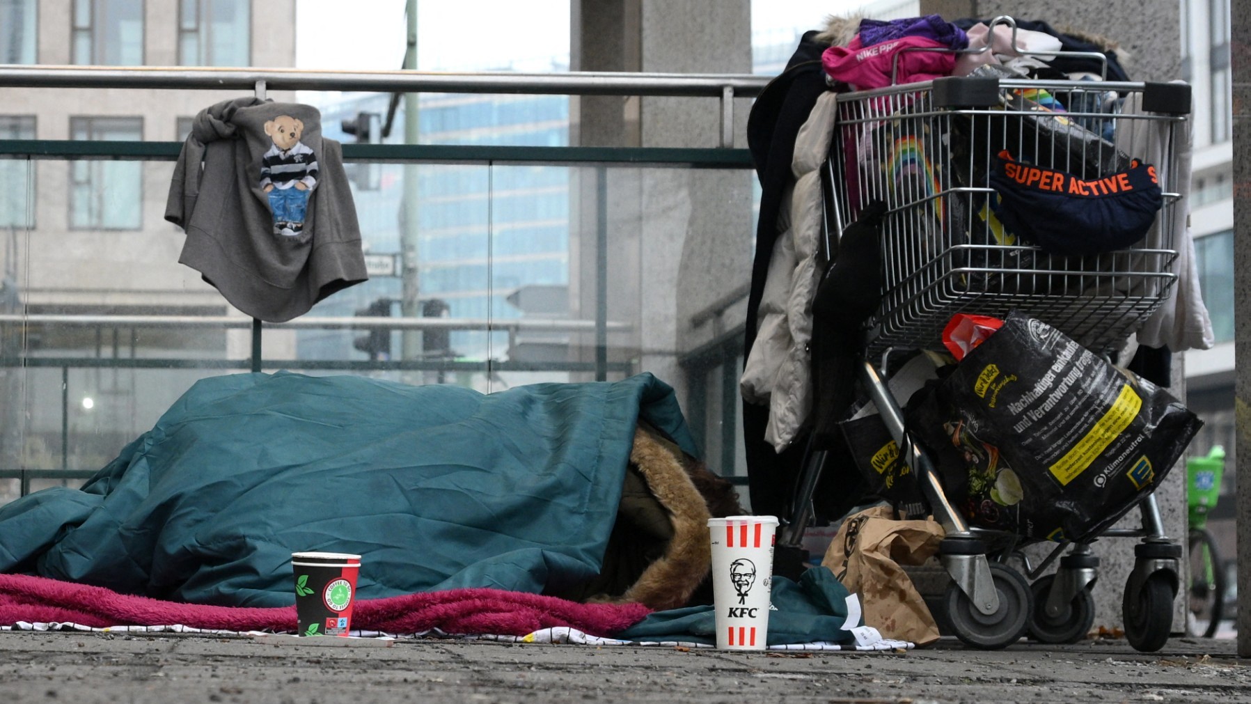 A homeless person sleeps under a blanket on the sidewalk near the central train station in Berlin, on February 10, 2026.