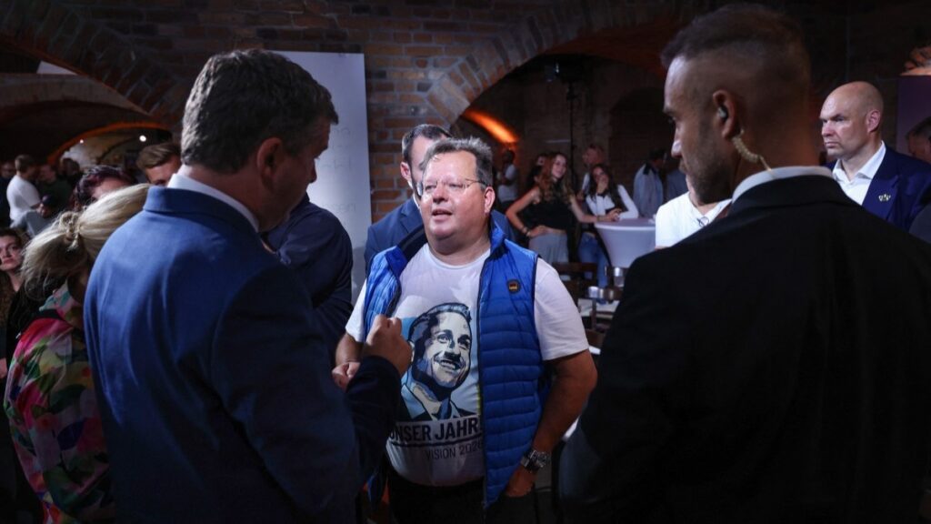Saxony-Anhalt’s State Premier and CDU main candidate Sven Schulze (L) talks with a spectator wearing a T-shirt with the portrait of AfD party main candidate Ulrich Siegmund after attending a live broadcast featuring the two leaders in Magdeburg, Germany, on September 4, 2026.
